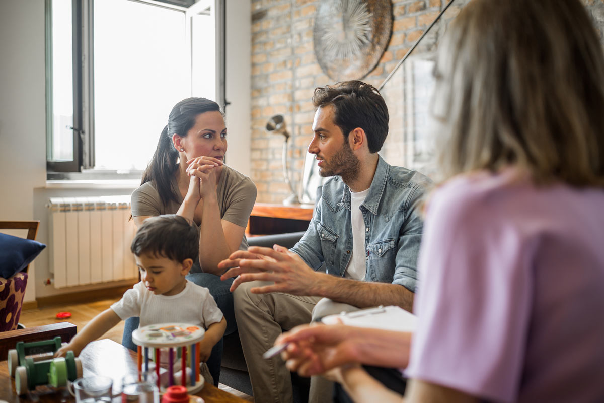 Foto einer Familie mit einer Familienberaterin: Vater, Mutter und ein kleiner Junge